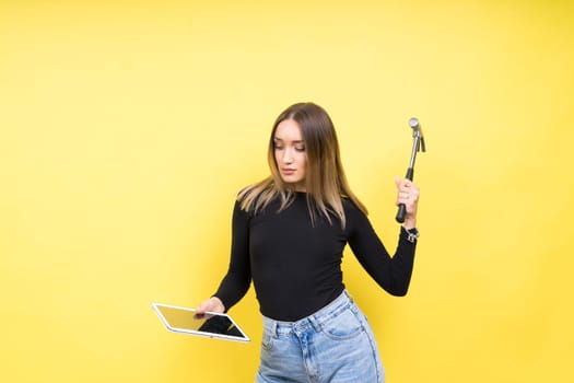 Woman with tablet and a hammer, Studio lighting yellow background isolated, copy space