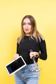 Woman with tablet and a hammer, Studio lighting yellow background isolated, copy space