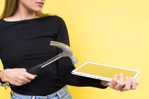 Woman with tablet and a hammer, Studio lighting yellow background isolated, copy space