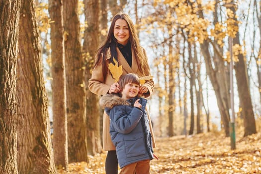 Cheerful woman and boy. Mother with her son is having fun outdoors in the autumn forest.