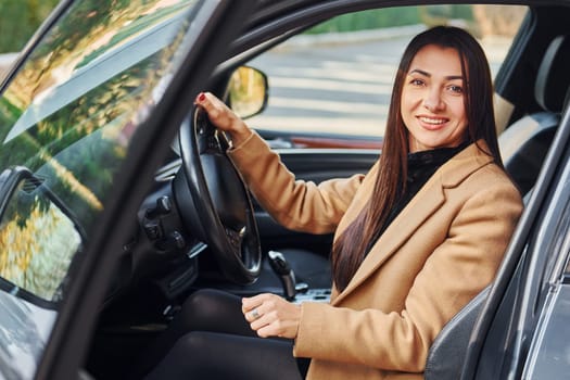 Woman is sitting in modern black colored automobile.