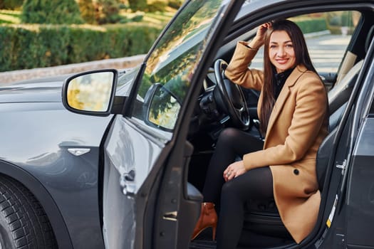 Woman is sitting in modern black colored automobile.