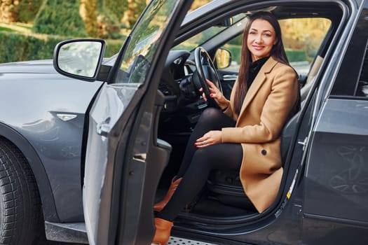 Woman is sitting in modern black colored automobile.