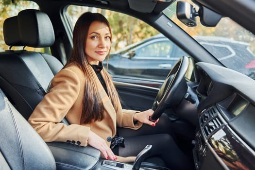 Vehicle interior. Woman is sitting in modern black colored automobile.