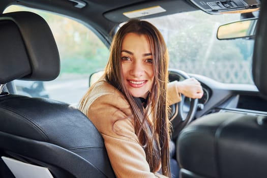 Vehicle interior. Woman is sitting in modern black colored automobile.