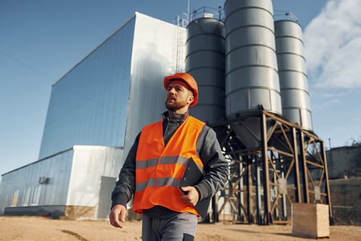 Building exterior. Construction worker in uniform is outdoors near the factory.