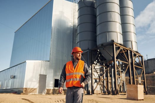 Building exterior. Construction worker in uniform is outdoors near the factory.