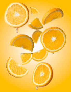 Various pieces of orange levitate on a yellow background, juicy fruit