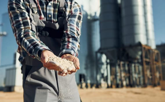 Holding soil. Construction worker in uniform is outdoors near the factory.