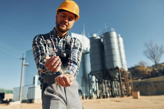 Holding soil. Construction worker in uniform is outdoors near the factory.