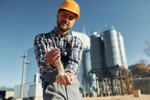 Holding soil. Construction worker in uniform is outdoors near the factory.
