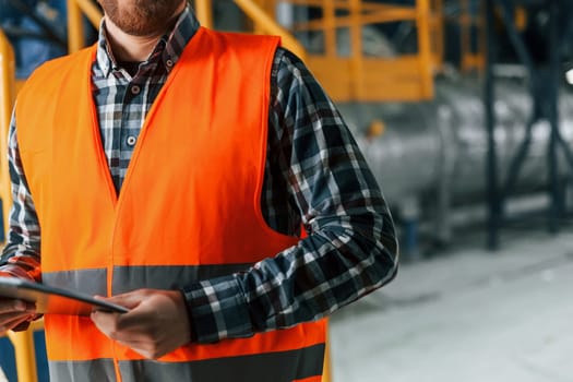 Close up view. Construction worker in uniform is in the factory.
