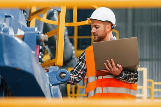 Close up view. Construction worker in uniform is in the factory.