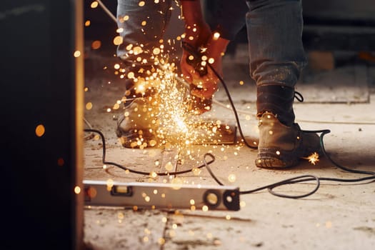 Sparks flying. Close up view of man's legs and hands with slicing tool. Working with metal.