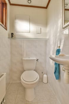 a small bathroom with white tiles and brown trim on the walls, along with a toilet in the corner next to the sink
