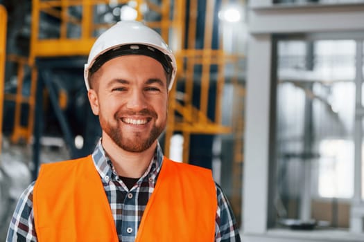 Portrait of construction worker in uniform is in the factory.