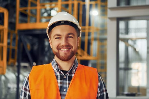 Portrait of construction worker in uniform is in the factory.