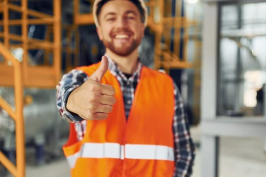 Portrait of construction worker in uniform is in the factory.