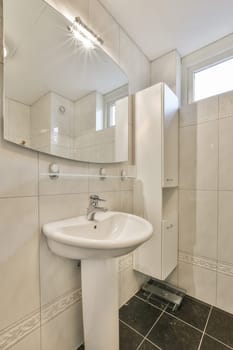 a bathroom with a sink, mirror and toilet paper on the wall next to it is a black tile floor