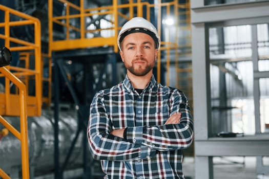 Posing for camera. Construction worker in uniform is in the factory.