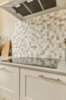 a kitchen with white cabinets and gray tiles on the backs of the range hood over the sink is in front of the stove