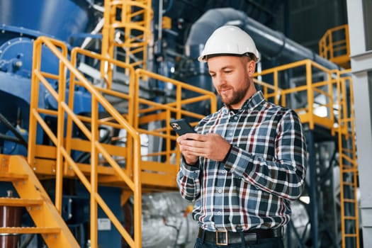 Posing for camera. Construction worker in uniform is in the factory.