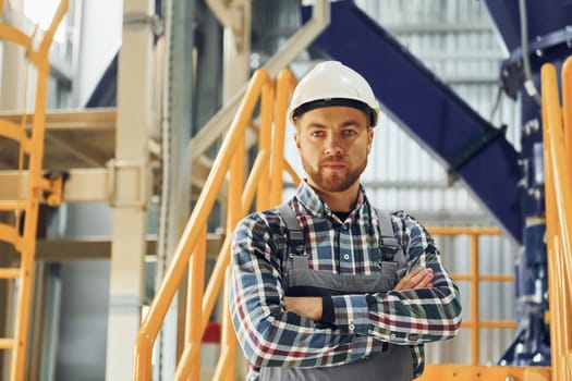Engineer is indoors. Construction worker in uniform is in the factory.
