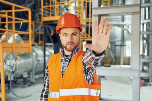 Looking forward. Construction worker in uniform is in the factory.