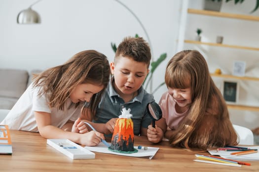 Building volcano from plasticine. Kids having fun in the domestic room at daytime together.