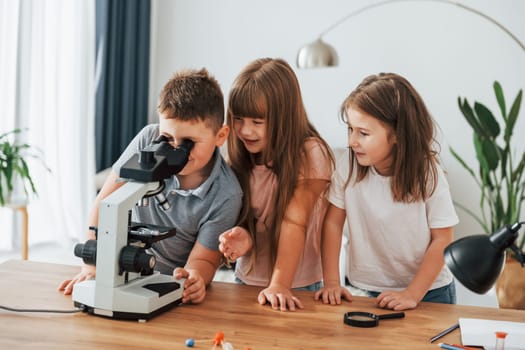 Using microscope. Kids having fun in the domestic room at daytime together.
