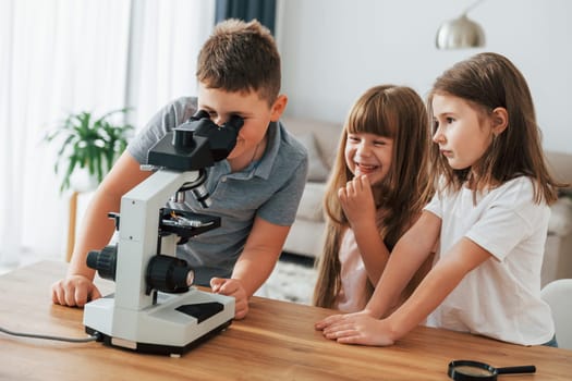 With microscope. Kids having fun in the domestic room at daytime together.
