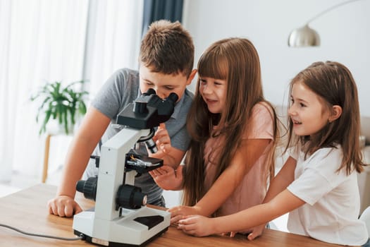 With microscope. Kids having fun in the domestic room at daytime together.