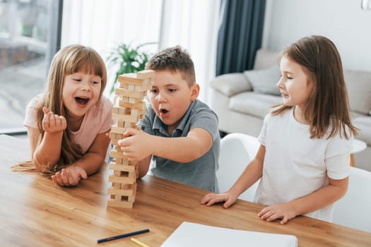 Building a tower. Playing game. Kids having fun in the domestic room at daytime together.