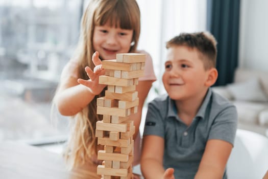 Building a tower. Playing game. Kids having fun in the domestic room at daytime together.