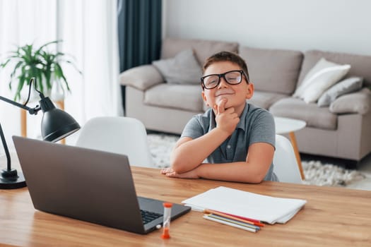 Little boy is having online lessons by using laptop at home.
