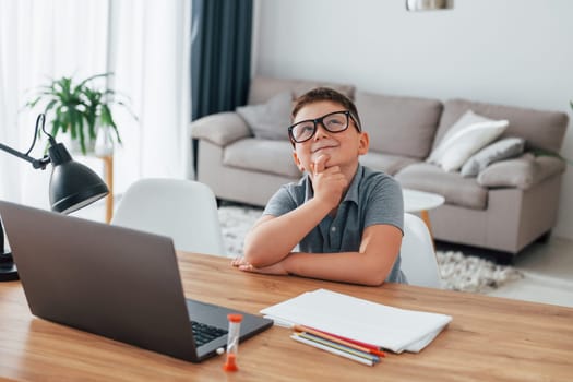 Little boy is having online lessons by using laptop at home.