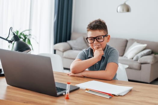 Little boy is having online lessons by using laptop at home.