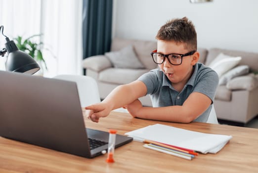 Little boy is having online lessons by using laptop at home.