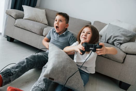 Playing videogames. Kids having fun in the domestic room at daytime together.