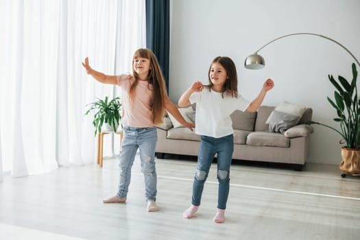 Dancing together. Kids having fun in the domestic room at daytime.