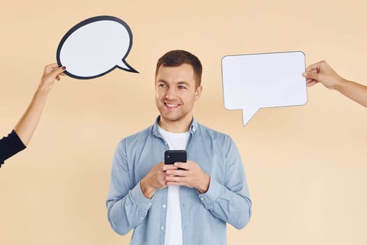 Holding smartphone. Many ideas. Man standing in the studio with empty signs for the text.