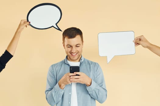 Holding smartphone. Many ideas. Man standing in the studio with empty signs for the text.