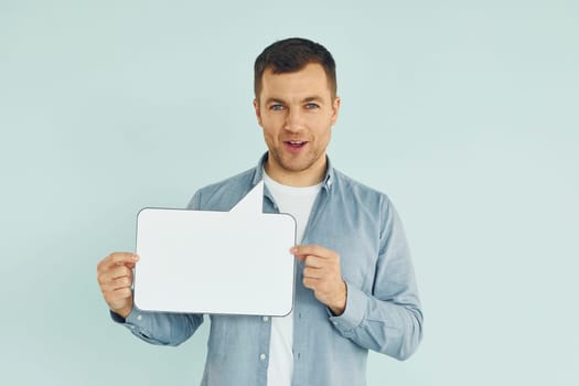 In casual clothes. Man standing in the studio with empty signs for the text.