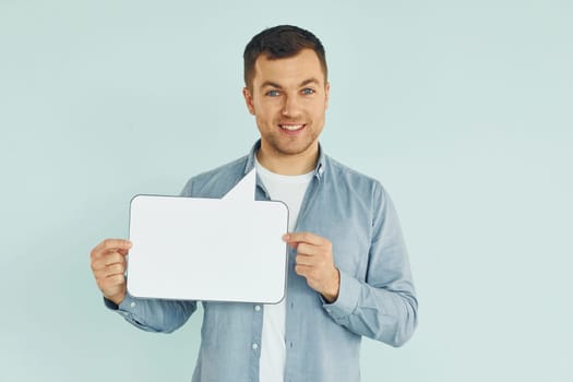 In casual clothes. Man standing in the studio with empty signs for the text.