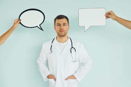 In doctor's uniform. Man standing in the studio with empty signs for the text.