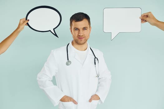 In doctor's uniform. Man standing in the studio with empty signs for the text.
