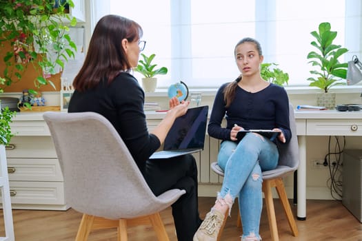 Teenage girl high school student talking with counselor, mentor, psychologist, social worker in the office. Adolescence, mental health, socialization, counseling, advice, psychology, therapy concept