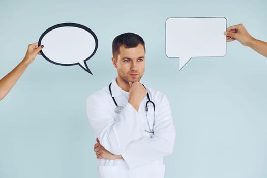 In doctor's uniform. Man standing in the studio with empty signs for the text.