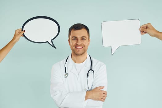In doctor's uniform. Man standing in the studio with empty signs for the text.