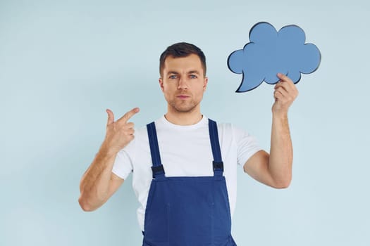 In blue uniform. Man standing in the studio with empty signs for the text.